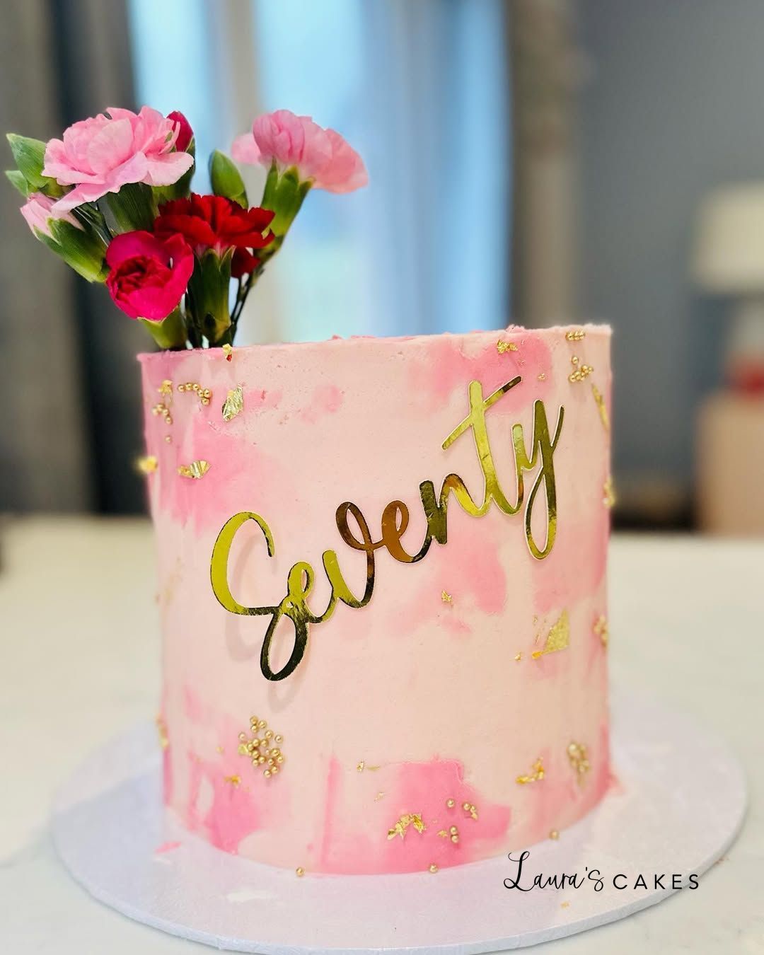 Celebration cake: A pink cake with gold foil lettering and a pink flower