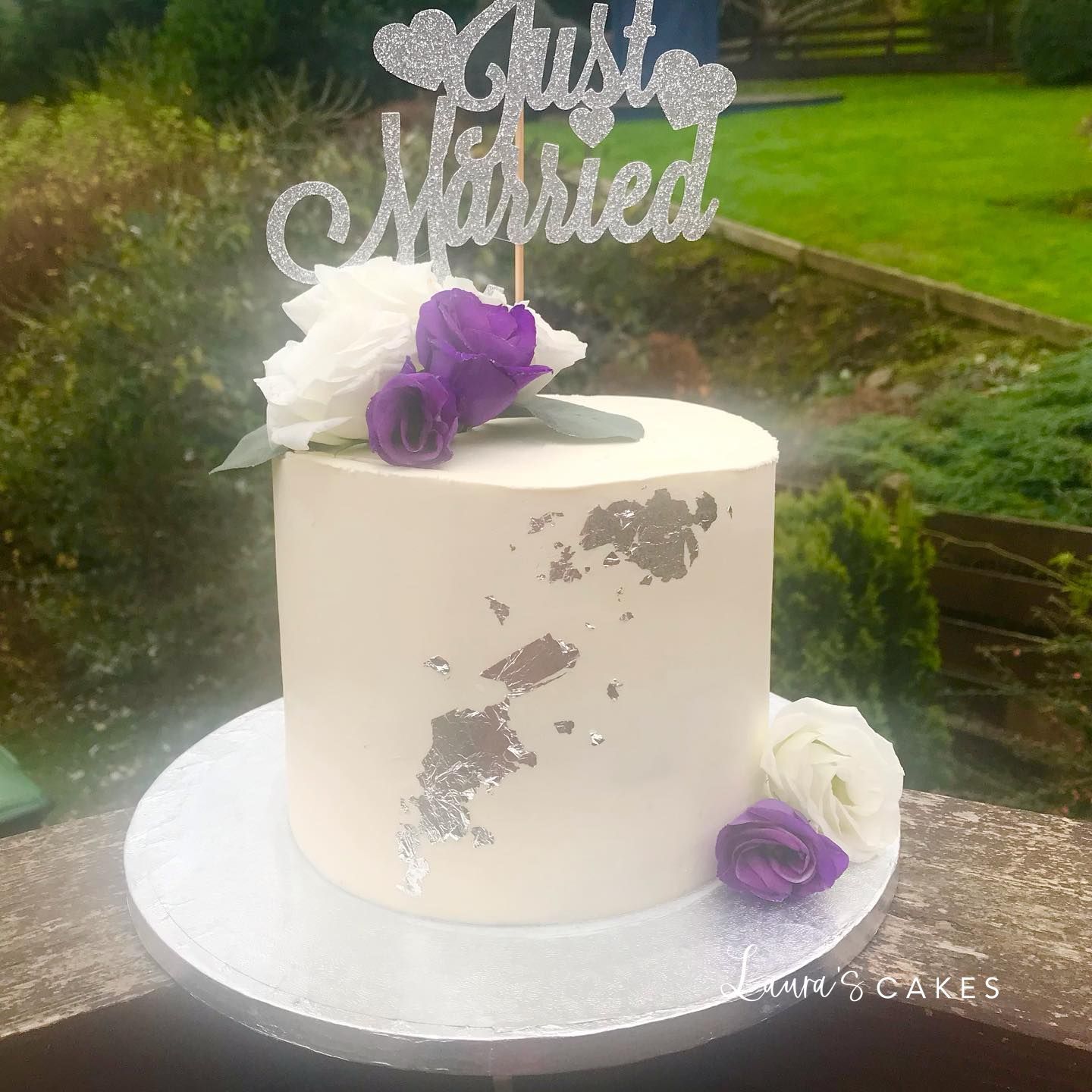 Celebration cake: A white cake with purple flowers and a silver cake topper