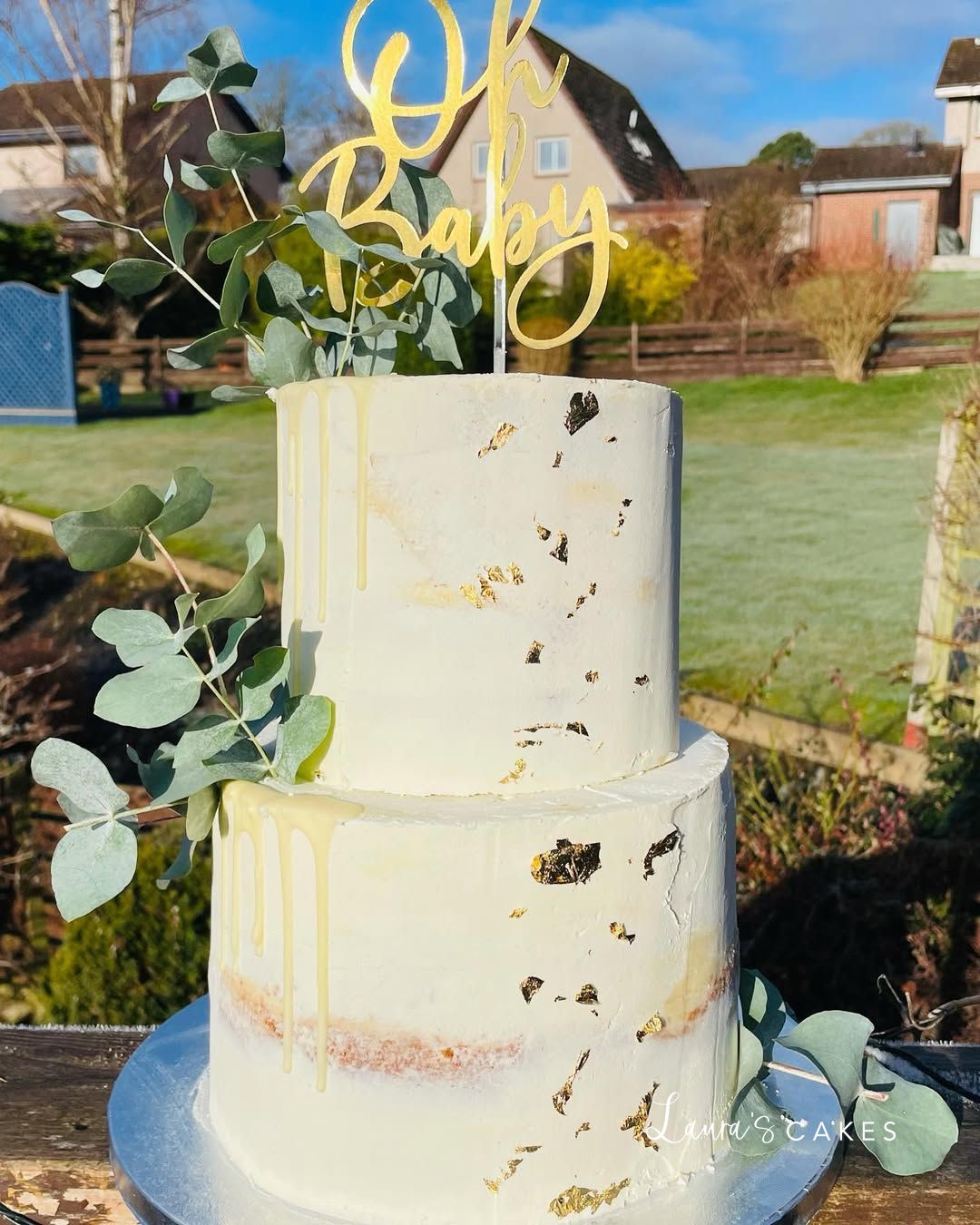 Celebration cake: A white wedding cake with gold and green leaves
